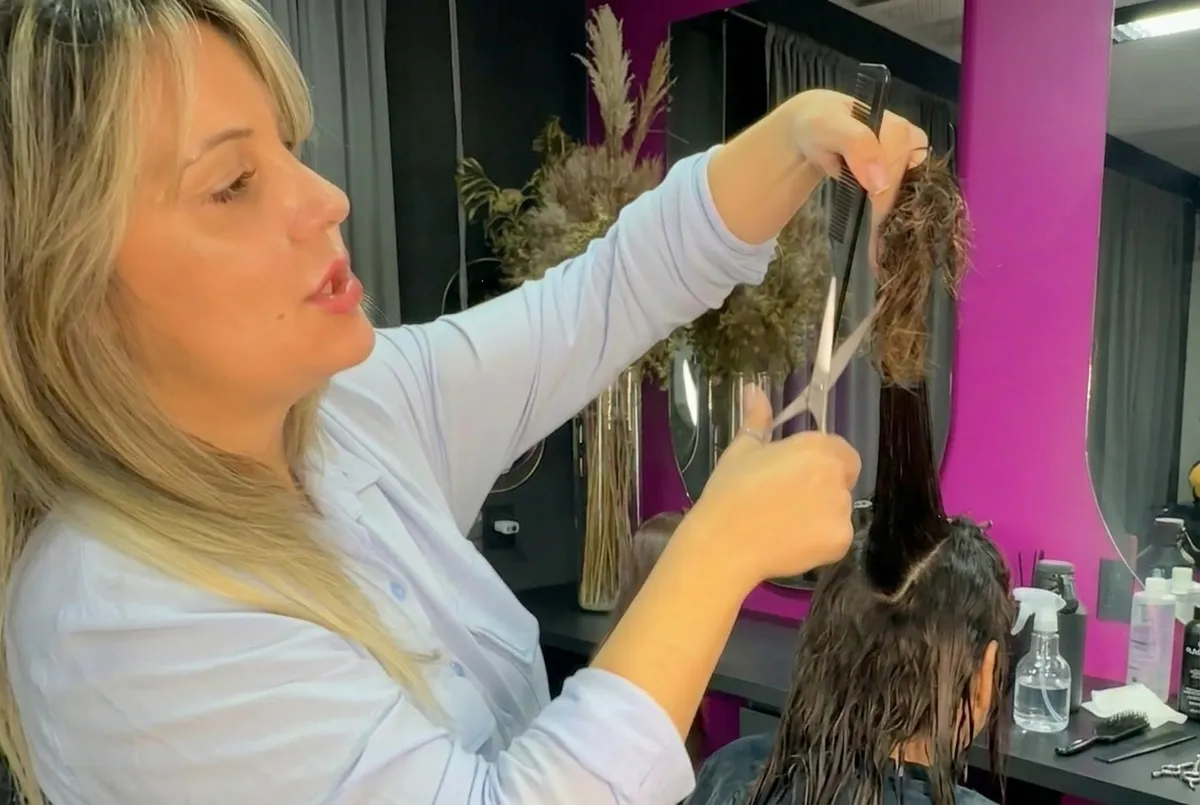 Cabeleireira profissional escovando cabelo de cliente no salão